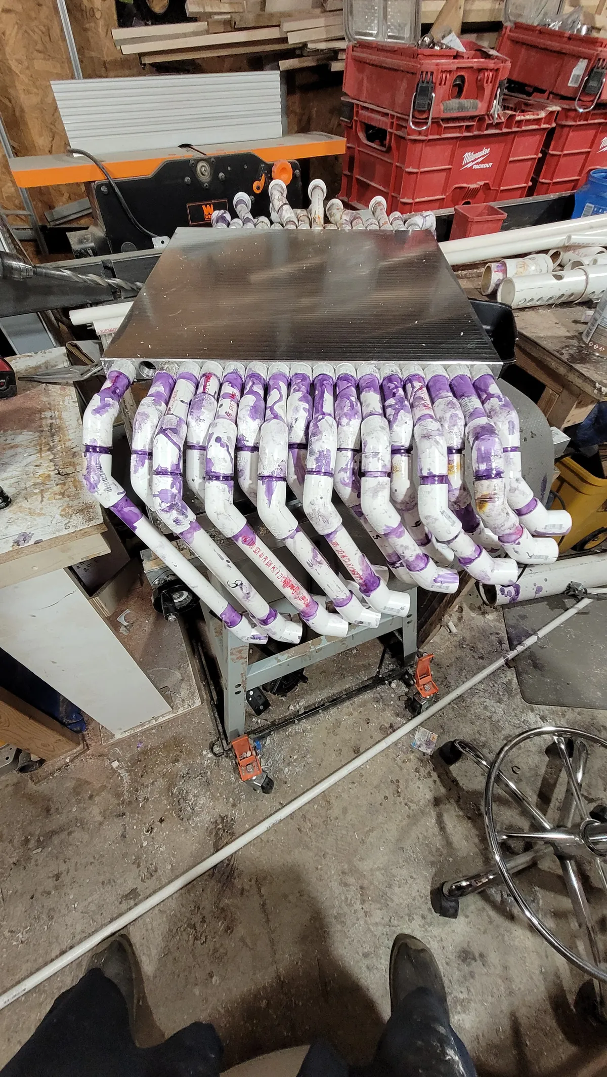 Aluminum cooling plate on a workbench with each of its 16 water passages plumbed to its own line